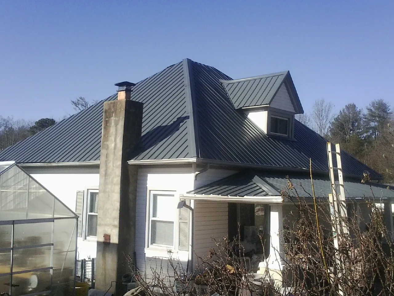Dark blue standing seam metal roof on a white farmhouse with dormer — Slate & Tile Roof Repair by Roofing Brothers in Pennsburg