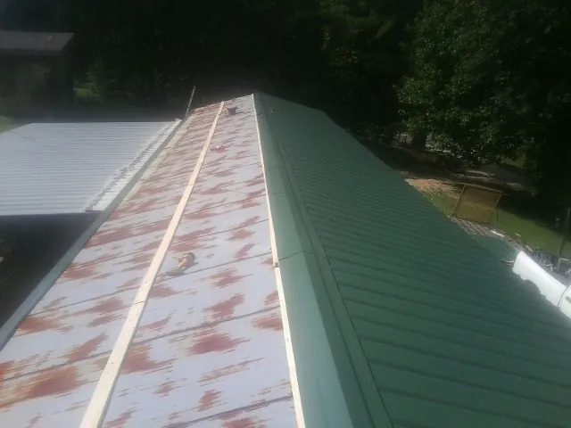 Old rusted panels beside newly installed green metal roofing — Wind Damage Roof Repair by Roofing Brothers in Pennsburg