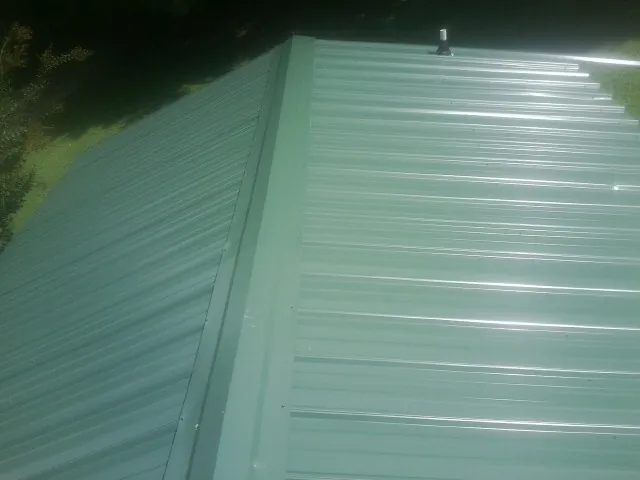 New green metal panels meeting at the ridge of a roof — Flat Roof Repair work by our crew in Pennsburg