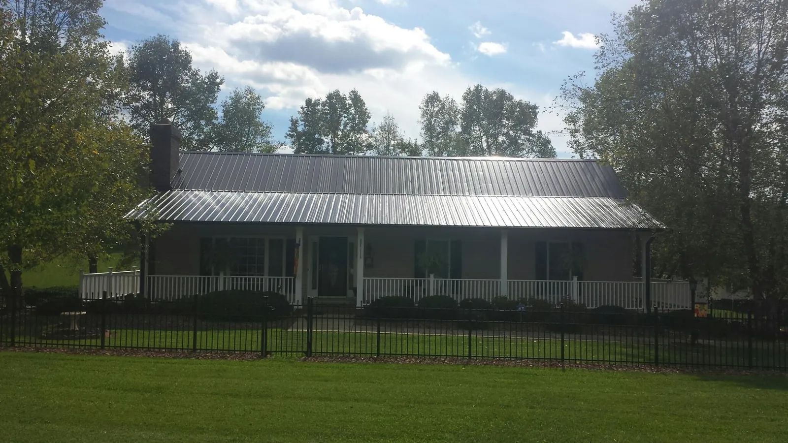 Gray metal roof on a brick ranch with a full width front porch — Gutter Guard Installation work by our crew in Pennsburg
