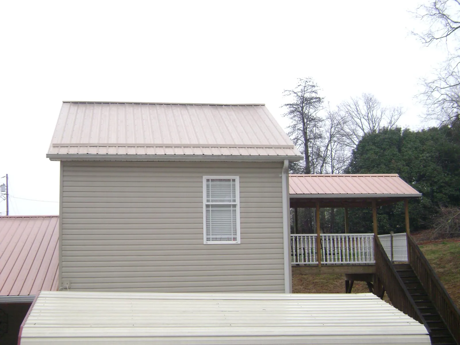 Tan metal roofs on a two story addition and attached porch, from a Roof Replacement job in Pennsburg