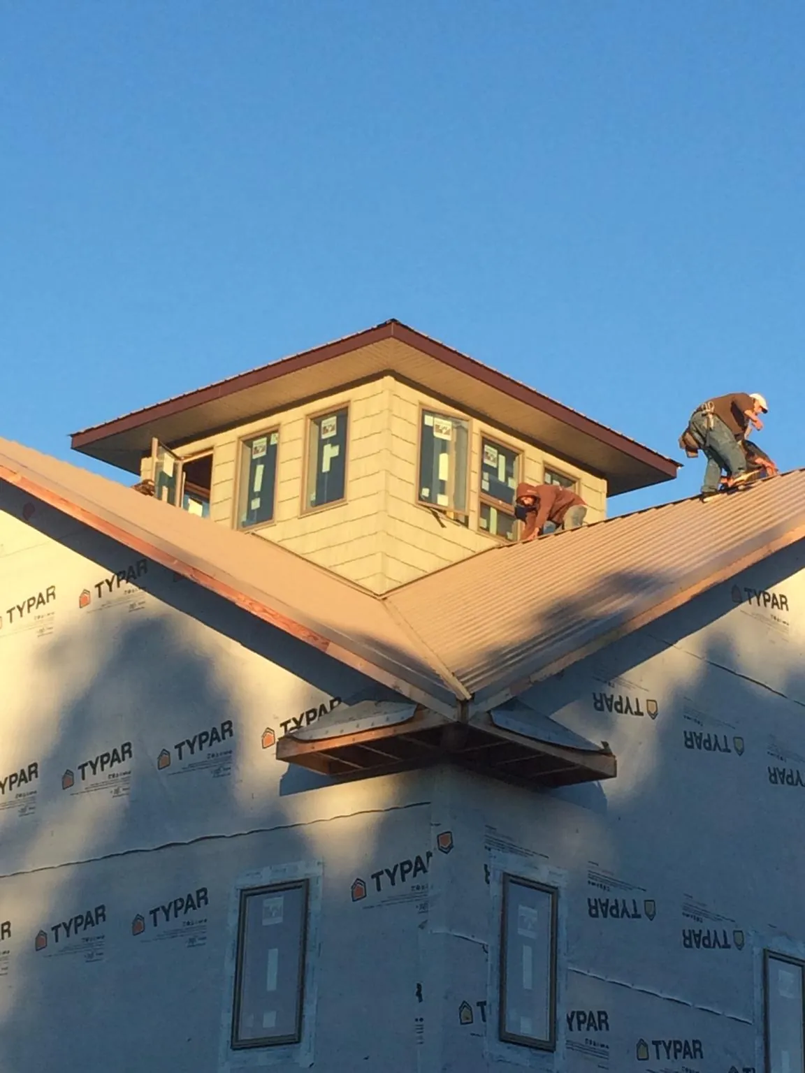 Roofers working around a rooftop cupola on a new metal roof at sunset — Roof Waterproofing in Pennsburg by Roofing Brothers